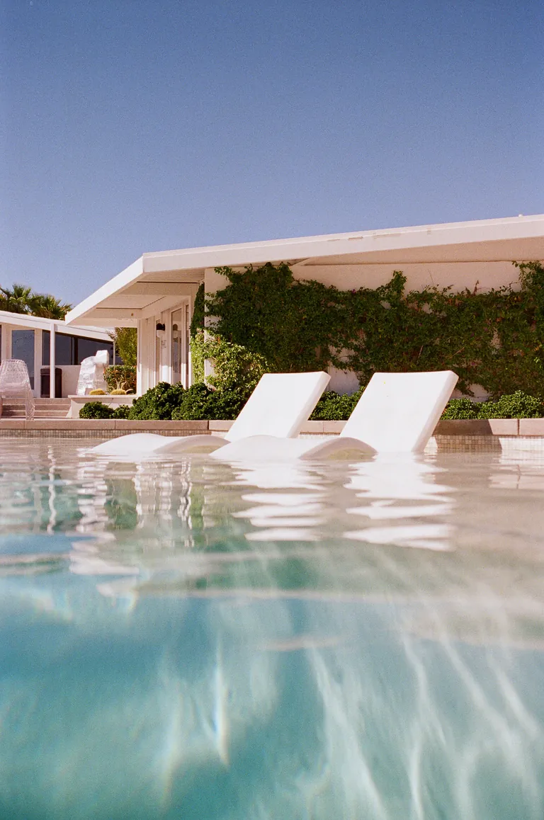 Two white sun loungers at the edge of a turquoise pool