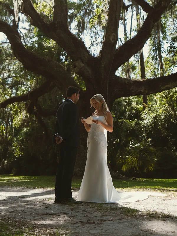 A couple reading their private vows beneath a live oak